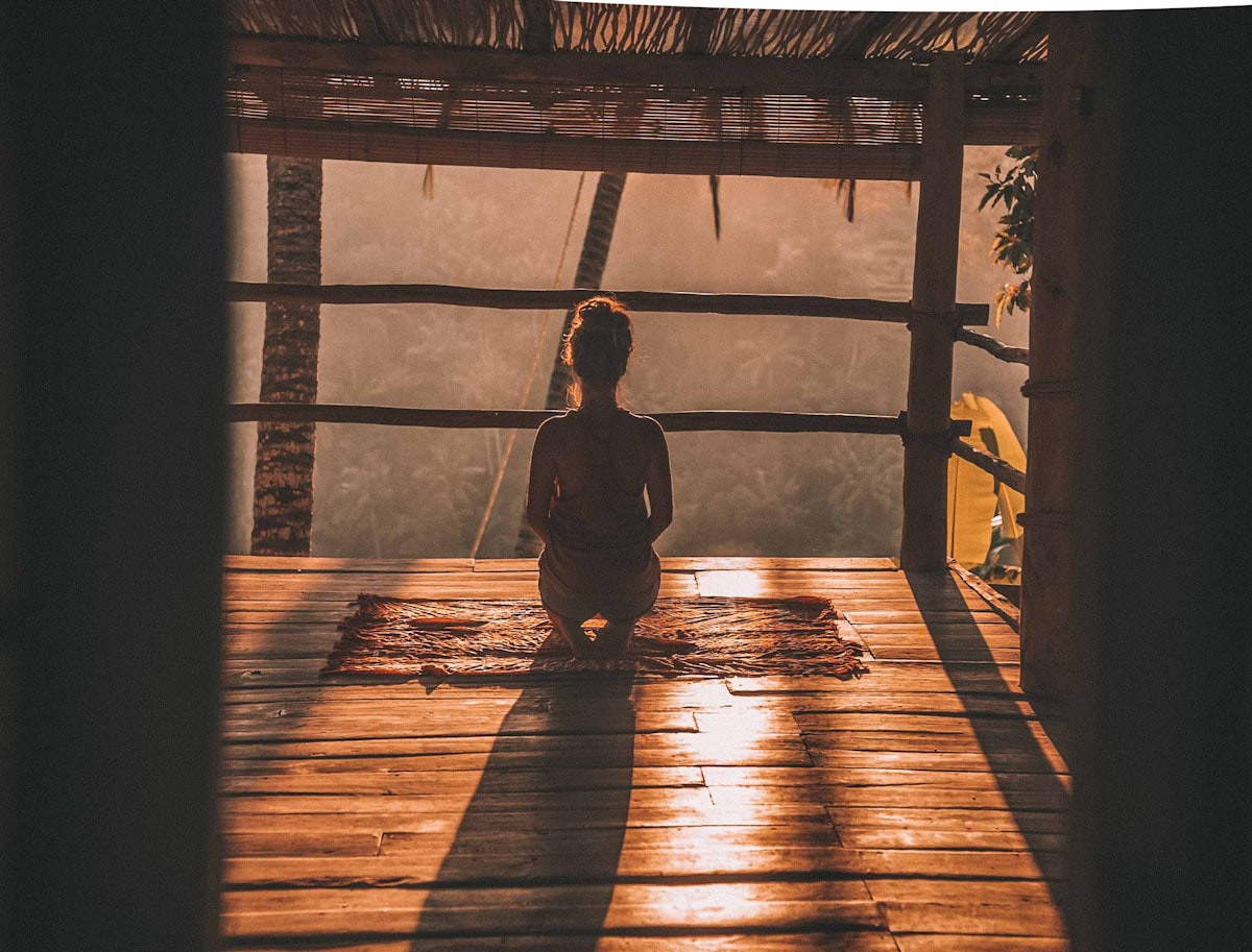 nainen meditoi trooppisessa maisemassa auringonvalossa.