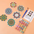 Thumbnail for Valmiiksi maalatut mandala-lasinaluset, maalit, siveltimet ja värikortti pöydällä