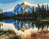 Thumbnail for Aurinko nousemassa lumihuippuisen vuoren takaa, maisema heijastuu tyynestä järvestä metsäisen rannan ympäröimänä – paint by numbers -maalaus.