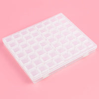 Thumbnail for Läpinäkyvä muovinen säilytyslokerikko, jossa on 56 pientä lokeroa timanttimaalauksen tarvikkeille. Laatikko on suljettuna vaaleanpunaisella taustalla.