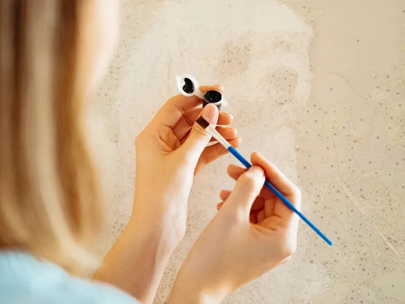 Numeromaalauksen lähikuva, jossa sivellin maalaa numeroitua kangasta